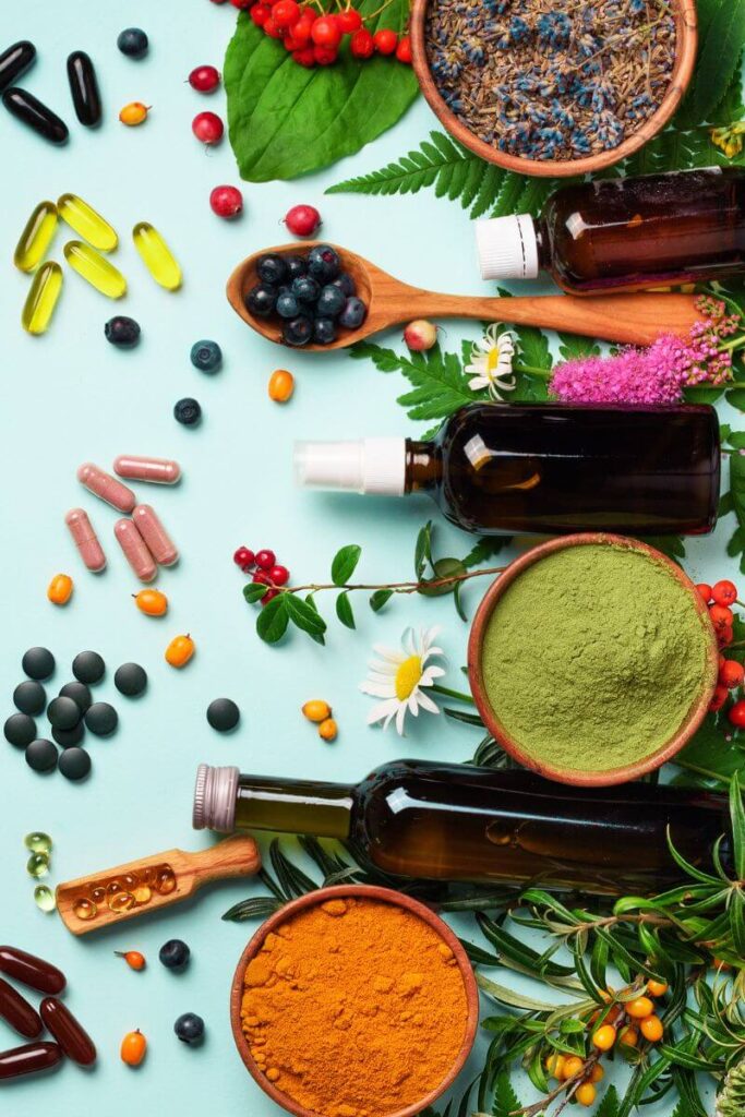 Biohacking at Your Health In Motion - plants, flowers, fruits, powders, clear amber bottles, and pills on an aqua background